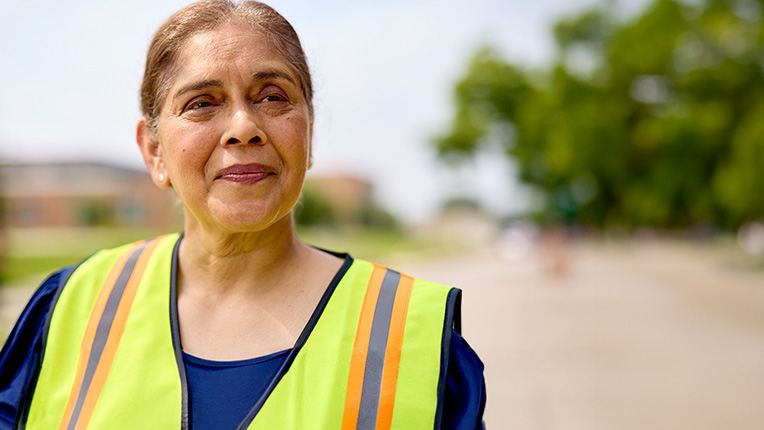 Smiling female crossing guard standing outside of a school