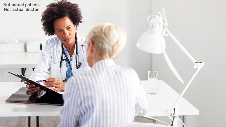 Woman talking to a female acting as a doctor in an exam room