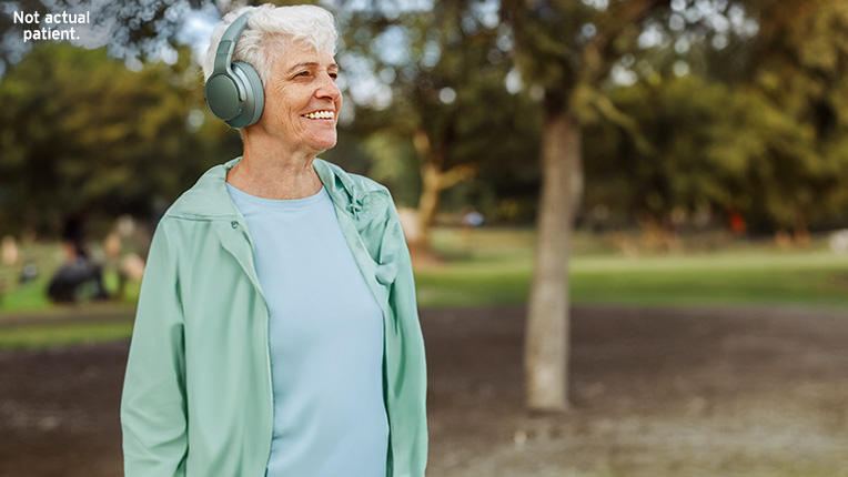 Woman smiling with headphones on while walking outside